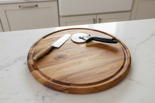 Round acacia wood cutting board with knife and pizza cutter on kitchen counter